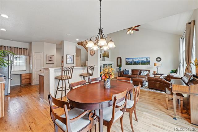 Open-plan dining and living area with an oval wood table, hardwood floors, and a breakfast bar.