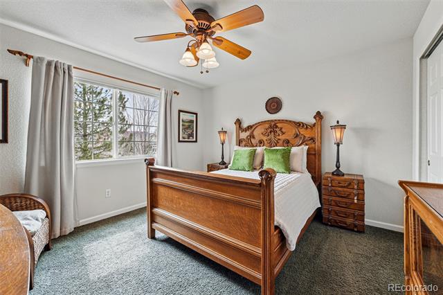 Bedroom with a carved wooden bed, green pillows, matching nightstands, and a ceiling fan.