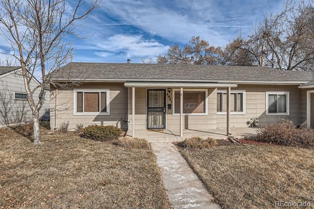Single-story beige house with a covered porch and concrete walkway through a dry front yard.