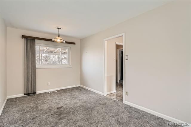 Vacant dining room with gray carpet, a curtained window, and a doorway to the tiled hall.