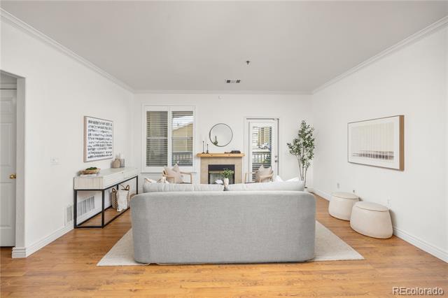 Staged living room with a gray sofa facing a fireplace between tall windows.