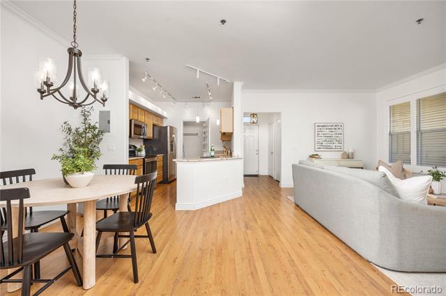 Open-plan condo living area with a white kitchen island, dining table, gray sofa, and light wood floors.