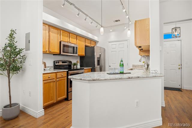 Kitchen with honey-colored cabinets, stainless steel appliances, and a large white island with a stone countertop.
