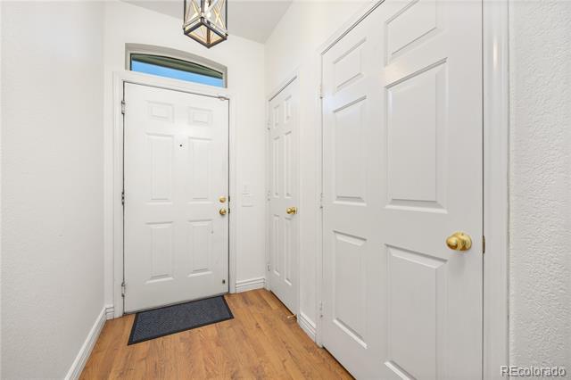 Entry hall with white paneled doors, warm wood flooring, and a glass transom above the front door.