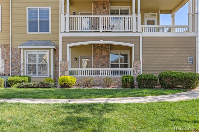 Condominium exterior with stone accents, covered balconies, white railings, and a landscaped lawn.