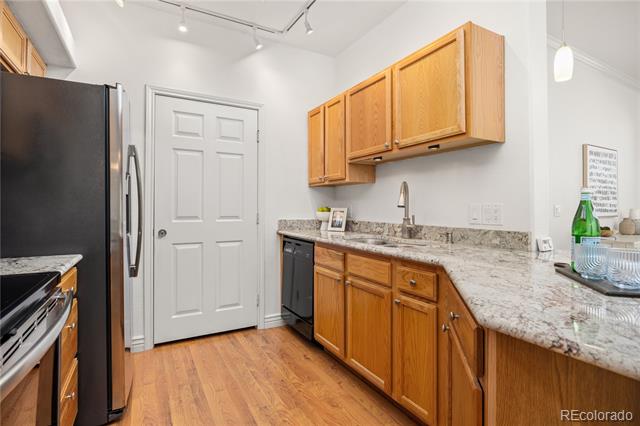 Kitchen with warm wood cabinets, granite counters, stainless steel appliances, and a white paneled door.