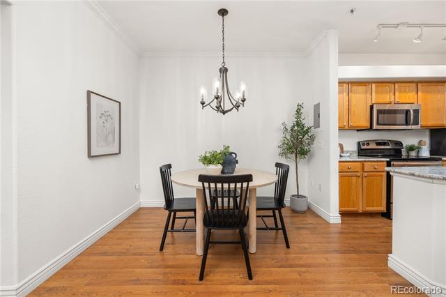 Dining area with a round table and chandelier beside a kitchen with warm wood cabinets.
