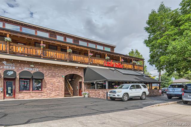 Brick commercial building with a long wooden balcony and storefront awning.
