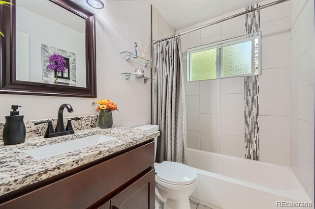 Bathroom with a granite vanity and tiled tub-shower enclosure with a frosted window.
