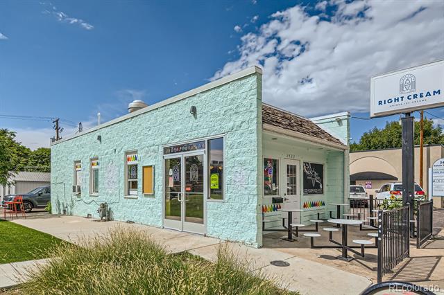 Mint-green ice cream shop with a roadside sign and fenced outdoor seating.