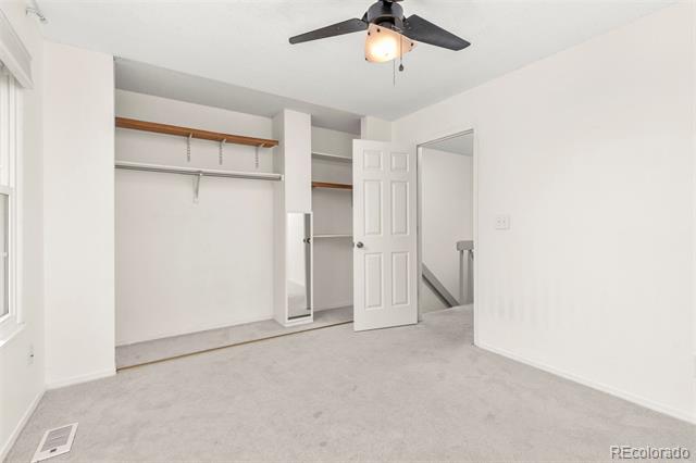Empty bedroom with a ceiling fan, carpet, and open closet.