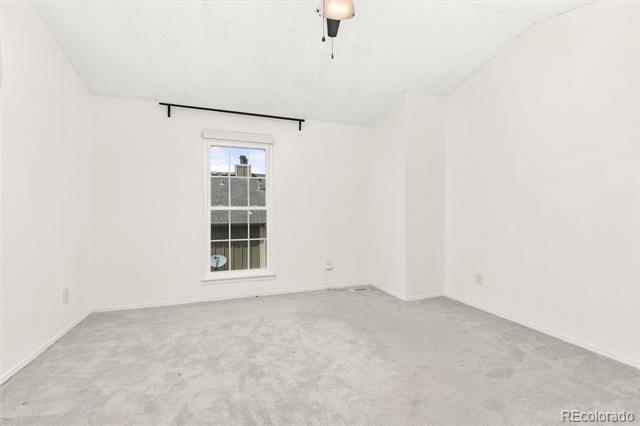 Vacant carpeted room with white walls, a single window, and a black curtain rod.
