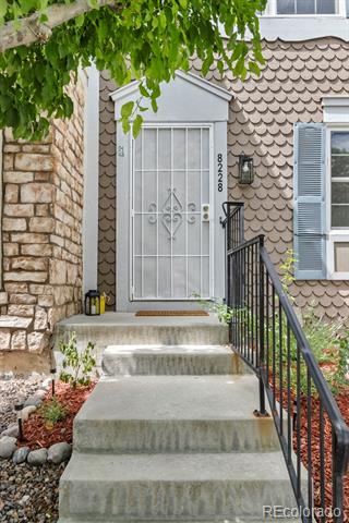 Home entrance with concrete steps, white security door, scalloped siding, and black metal railing.
