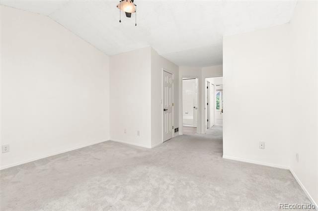 Empty carpeted bedroom with white walls and several doorways to the hallway.