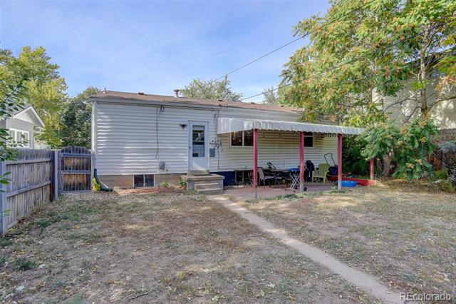 Single-story home with a covered patio and fenced backyard beneath mature trees.