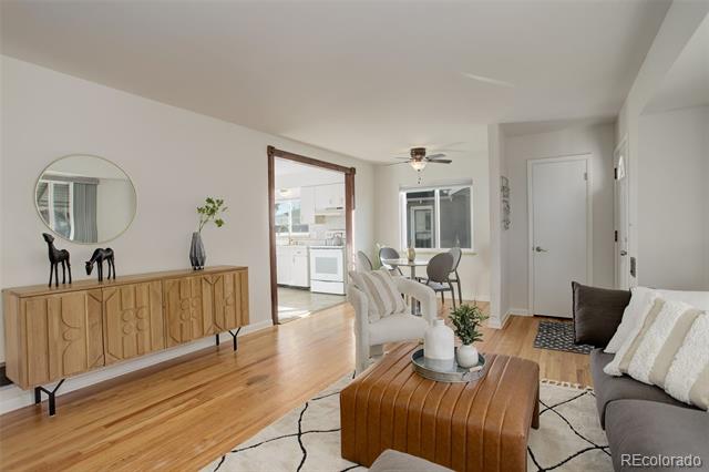 Living room with hardwood floors, a gray sofa, and an open kitchen and dining area.