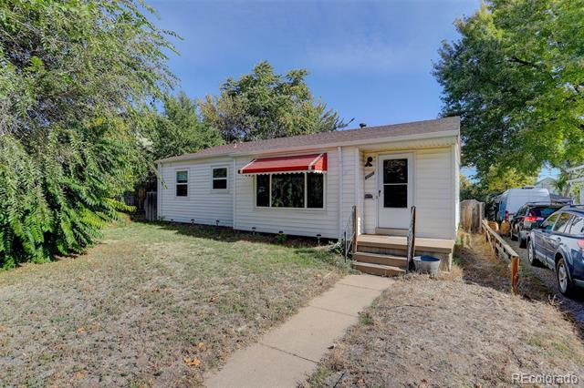 Single-story white house with a red window awning, entry steps, and a dry front yard.