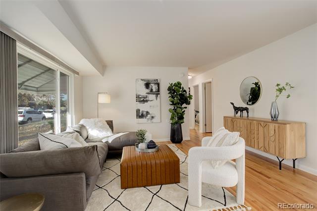 Living room with a gray sectional, white chair, wooden coffee table, and hardwood floors.