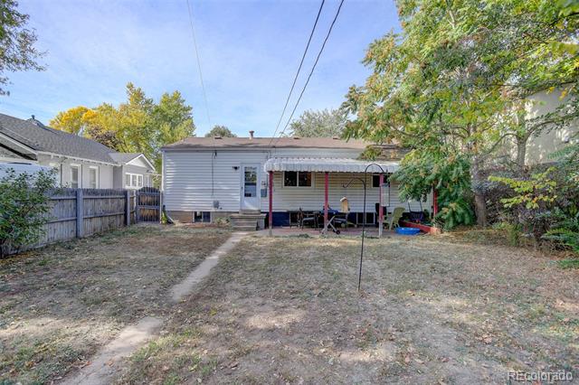 Rear of a single-story home with a covered patio and mostly dry, fenced backyard.
