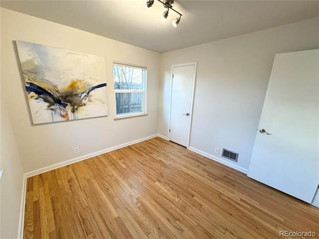 Empty room with hardwood floors, abstract wall art, and a window.