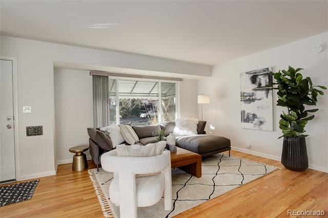 Staged living room with gray sectional, white accent chair, patterned rug, and large window.