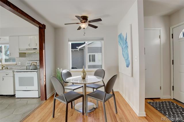 Dining area with a round glass table, four chairs, and an adjoining tiled kitchen.