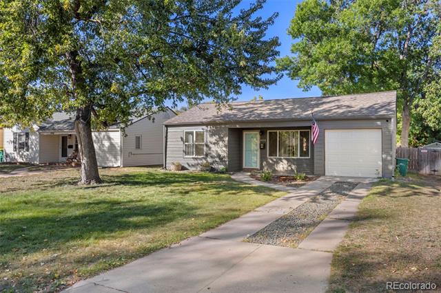 Single-story home with a garage, mature shade trees, and a concrete driveway.