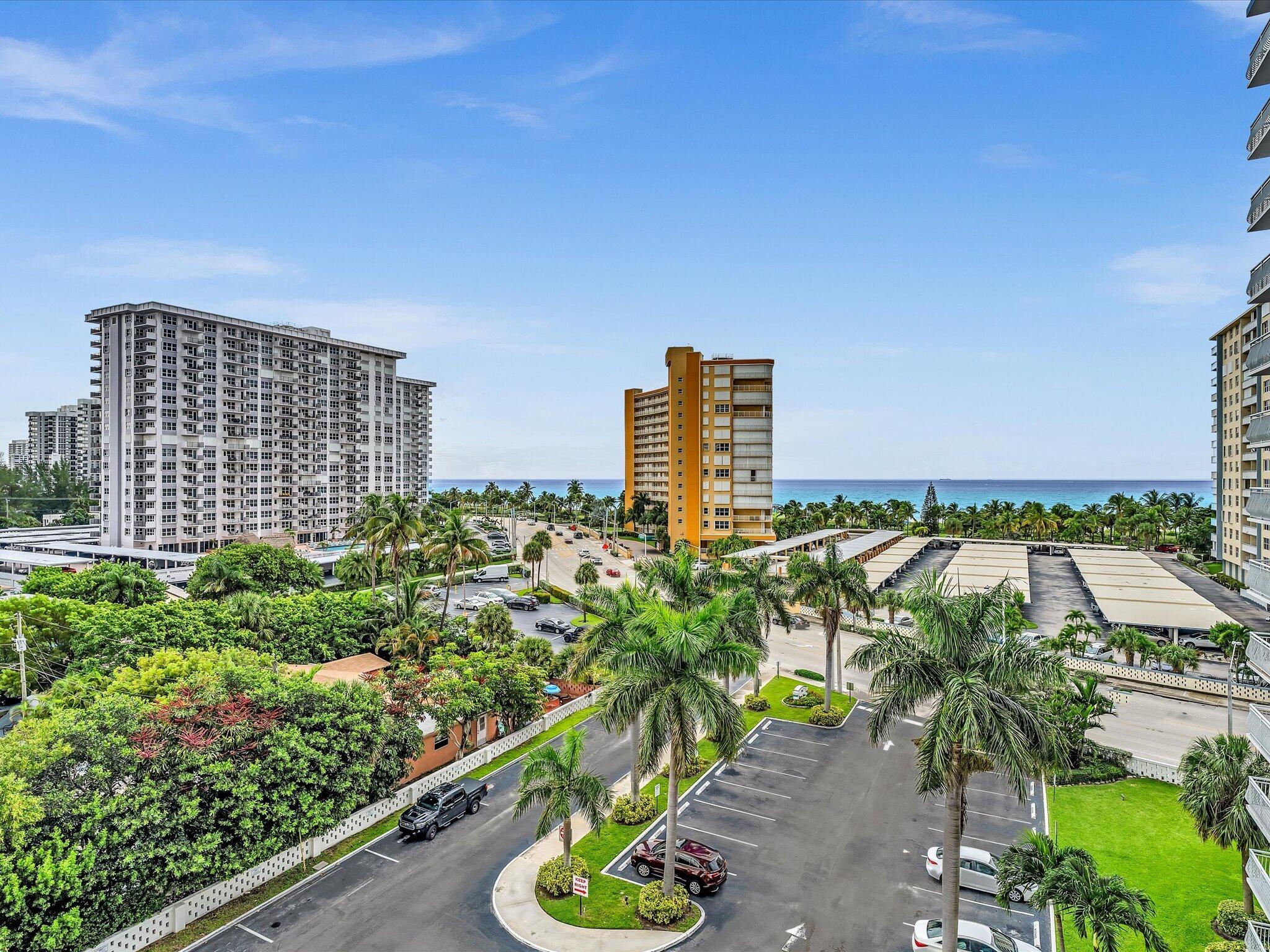 Elevated coastal view with condominium towers, palm-lined streets, and the Atlantic Ocean.