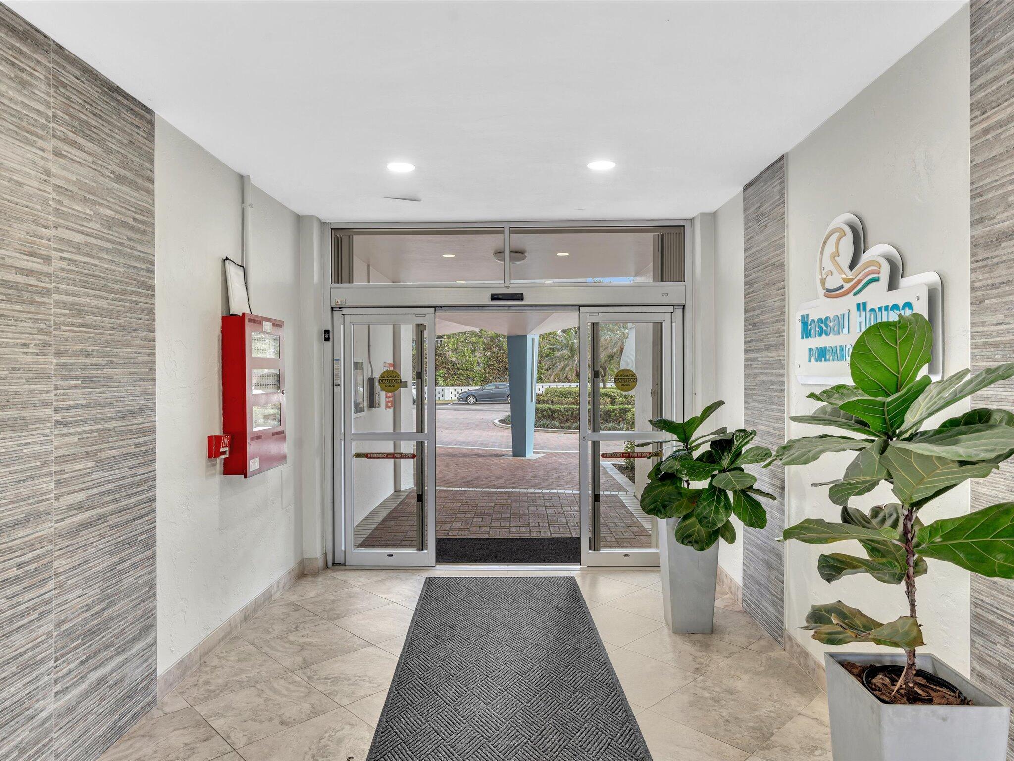 Nassau House lobby with automatic glass doors and large potted plants.