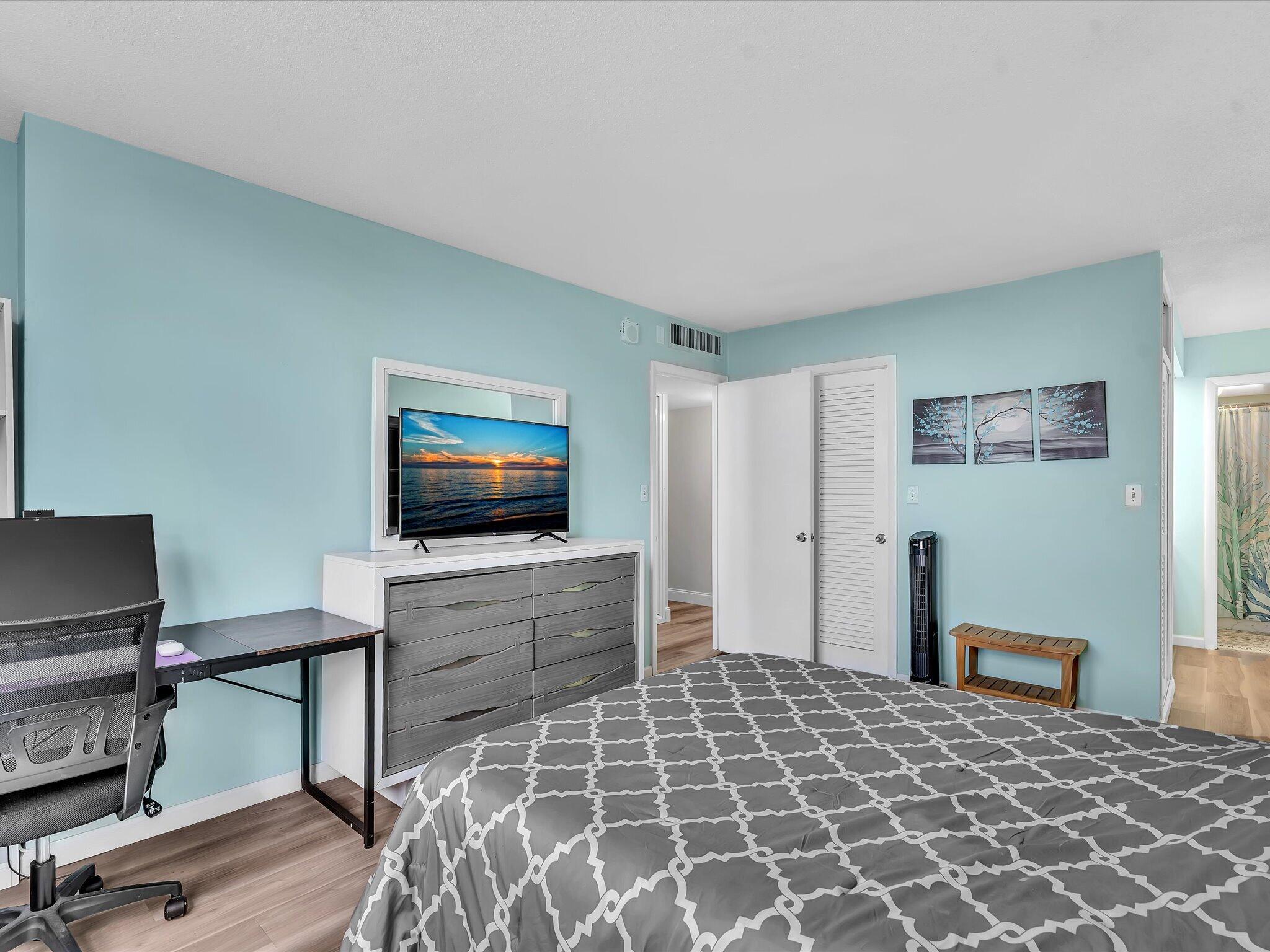 Bedroom with aqua walls, a gray patterned bed, and a television on a dresser.