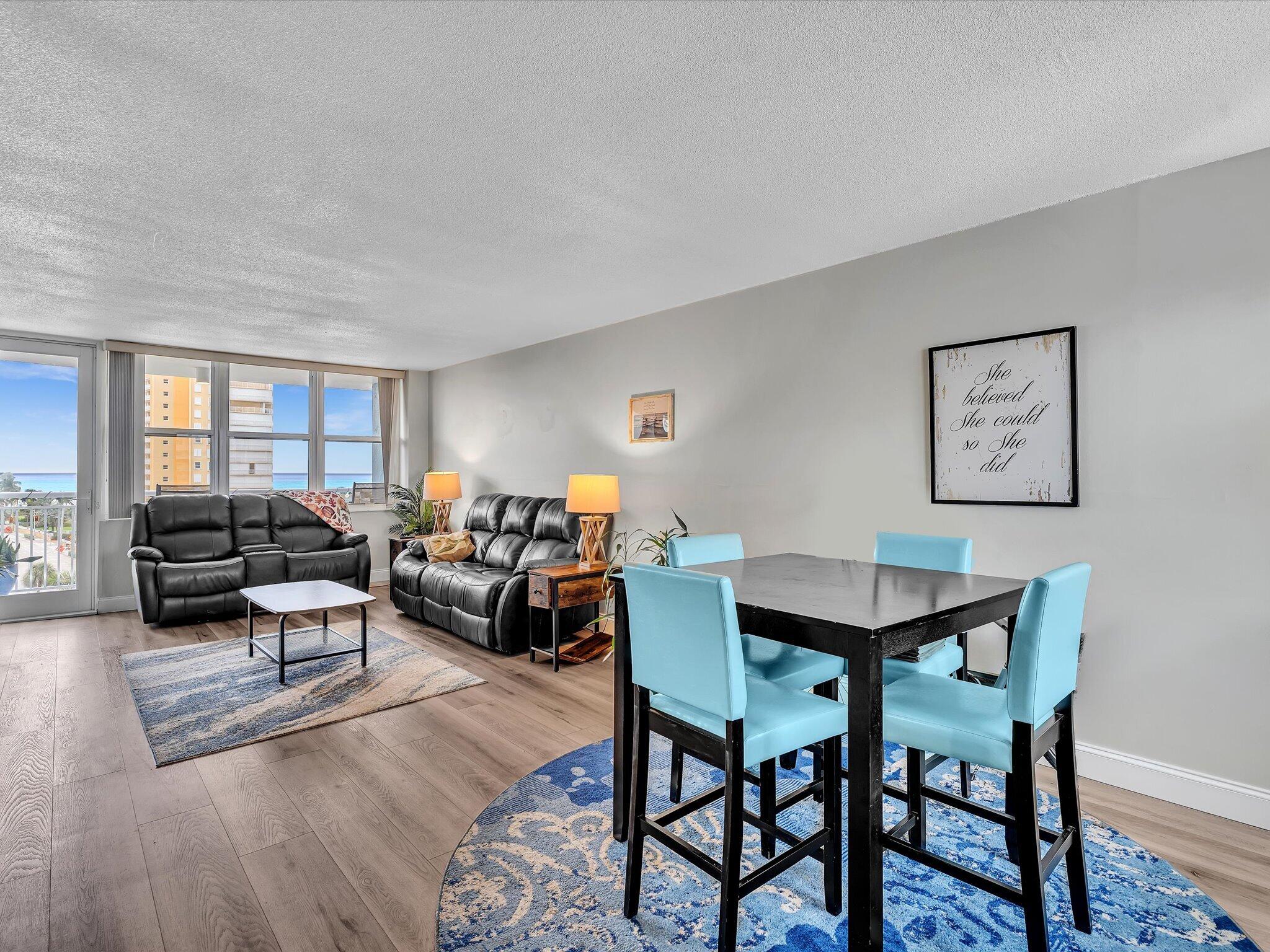 Furnished living and dining area with ocean views through large windows.