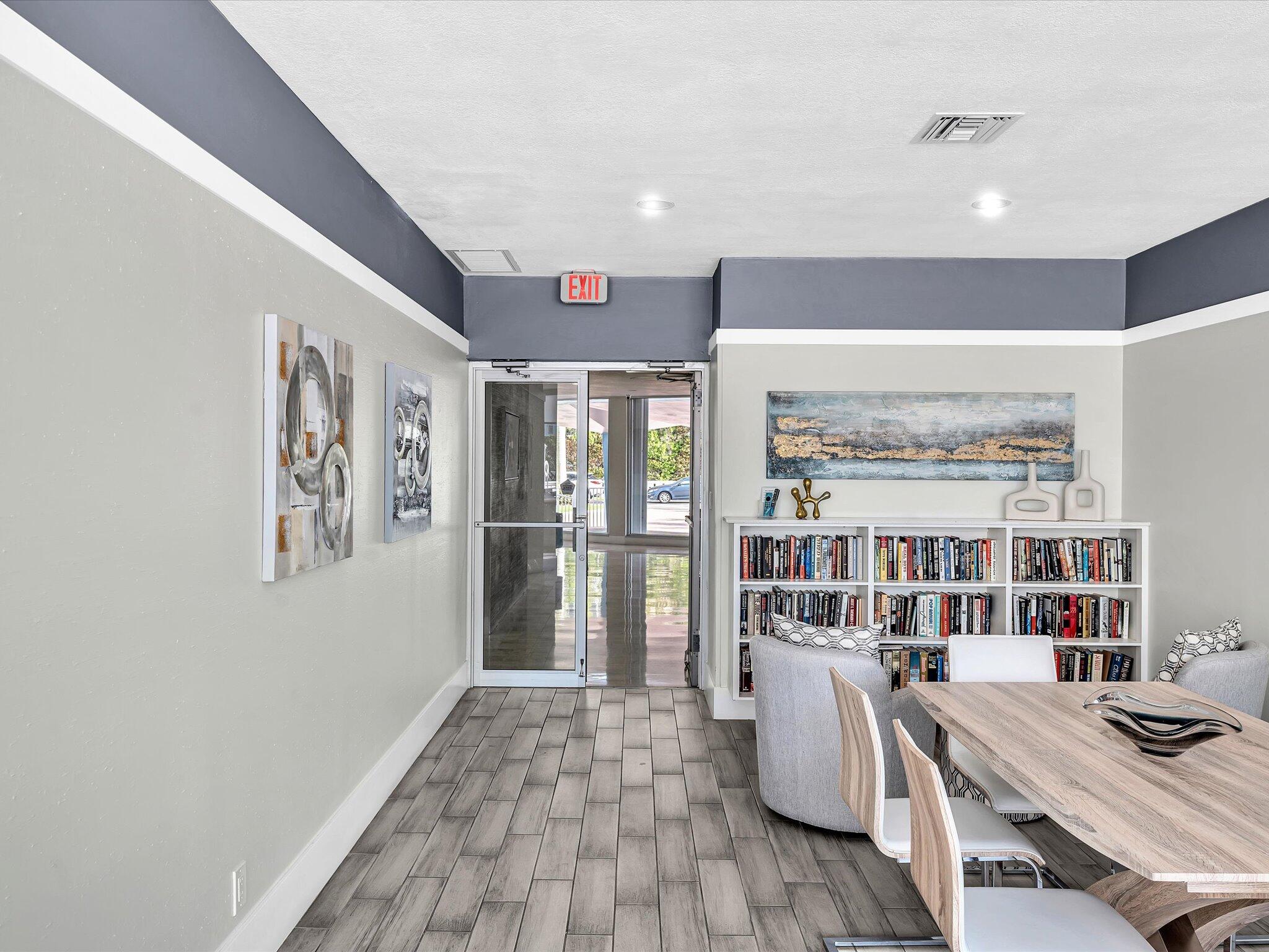 Furnished common area with a dining table, bookcases, and glass entrance doors.
