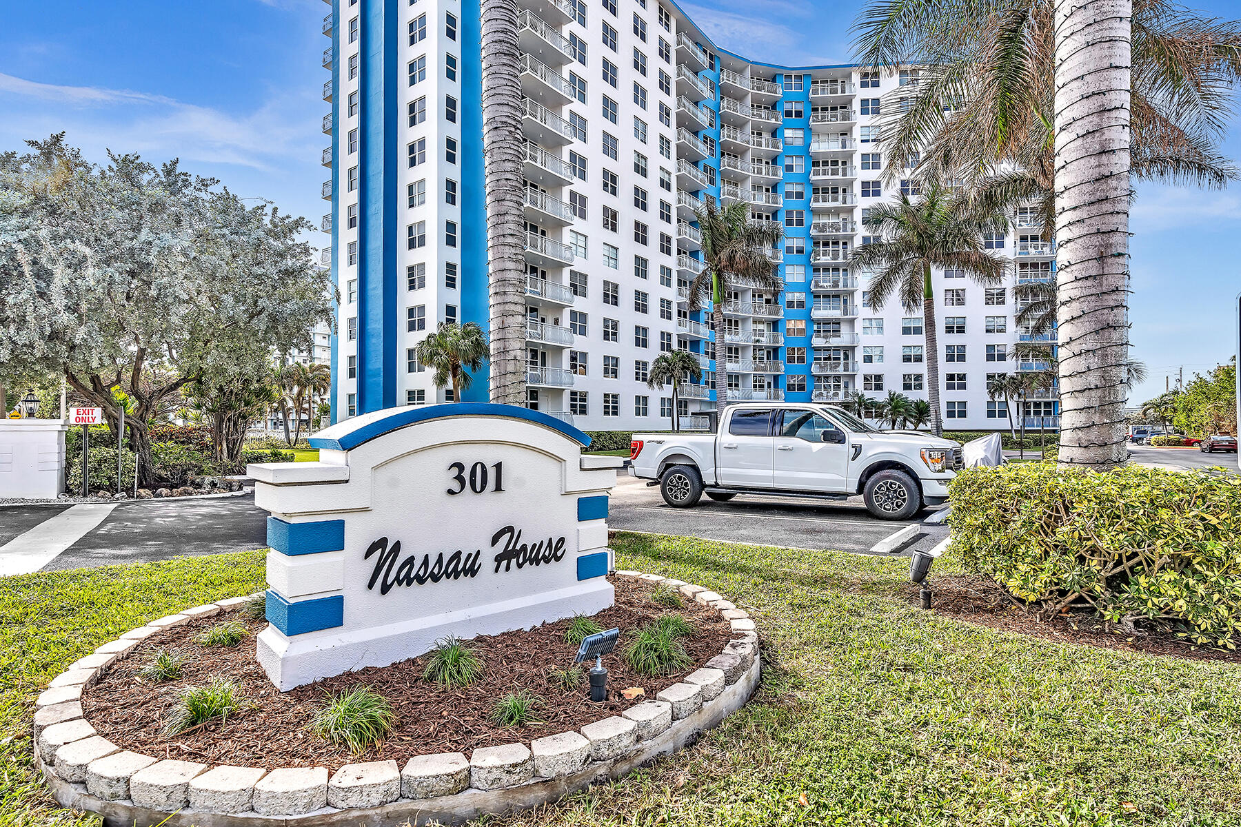 Nassau House condominium tower behind its landscaped 301 entrance sign.