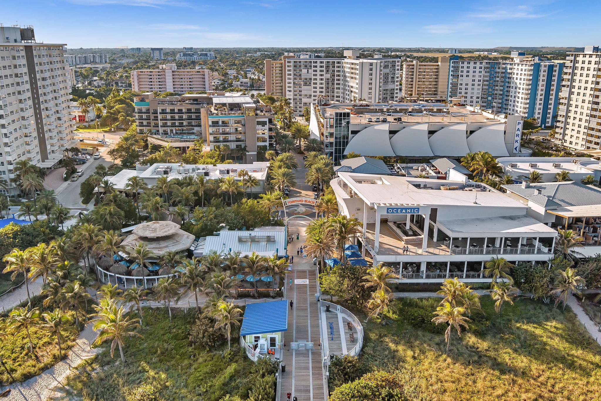 Aerial view of Pompano Beach condos, palm-lined boardwalk, and the Oceanic building.