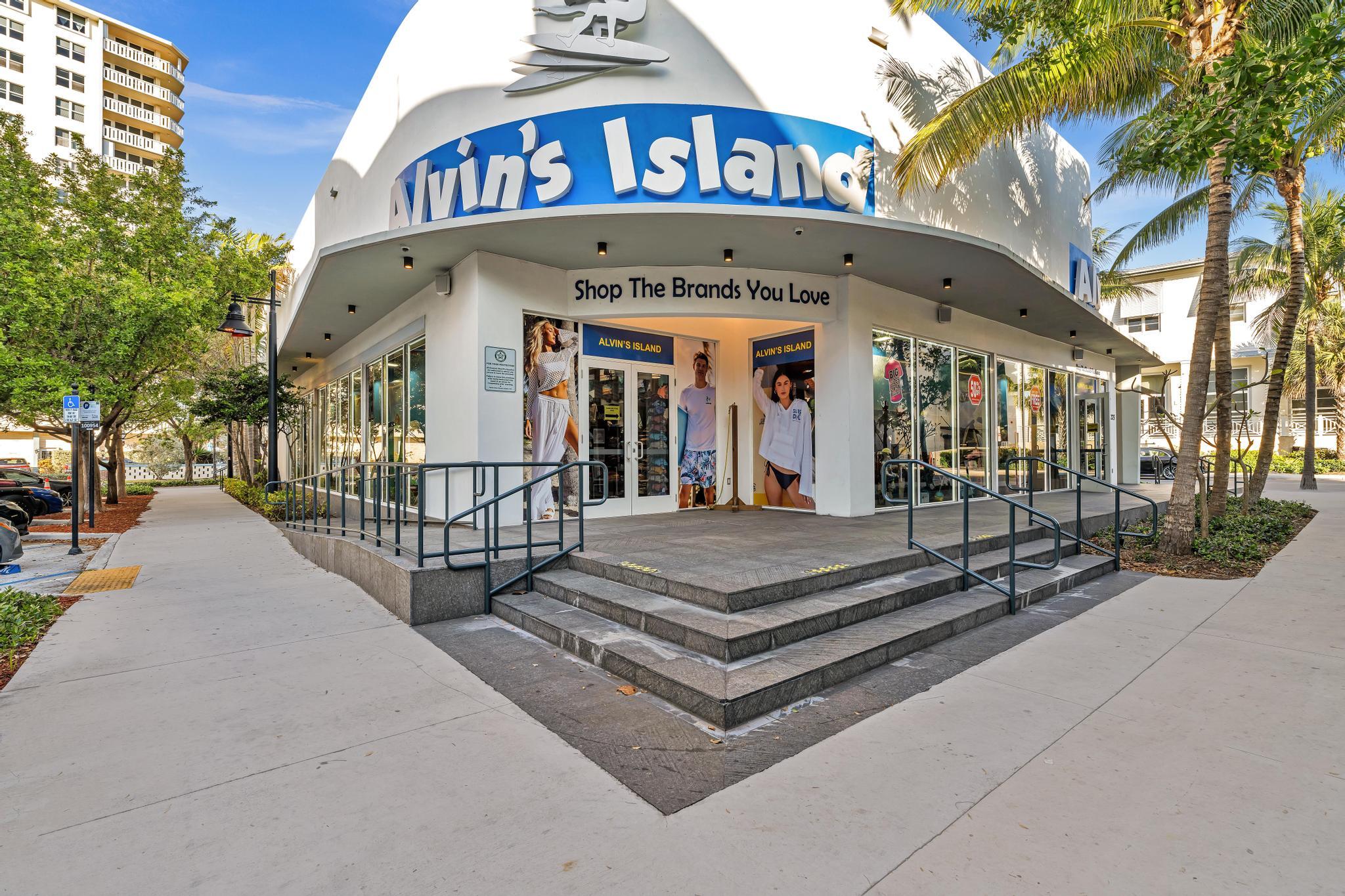 Alvin's Island storefront with a curved white facade, entrance steps, and palm trees.
