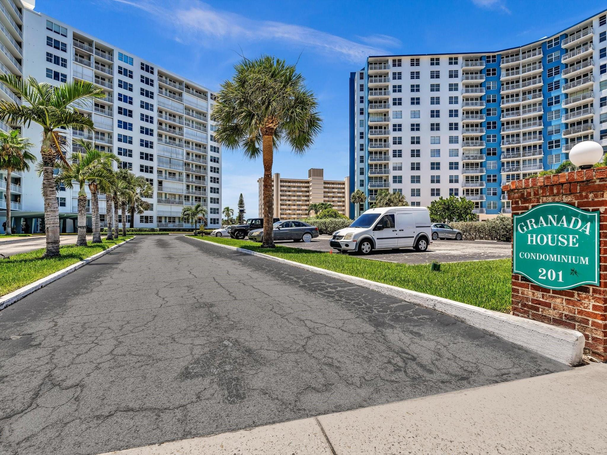 Granada House condominium buildings and entrance sign, with palm trees and a parking area.