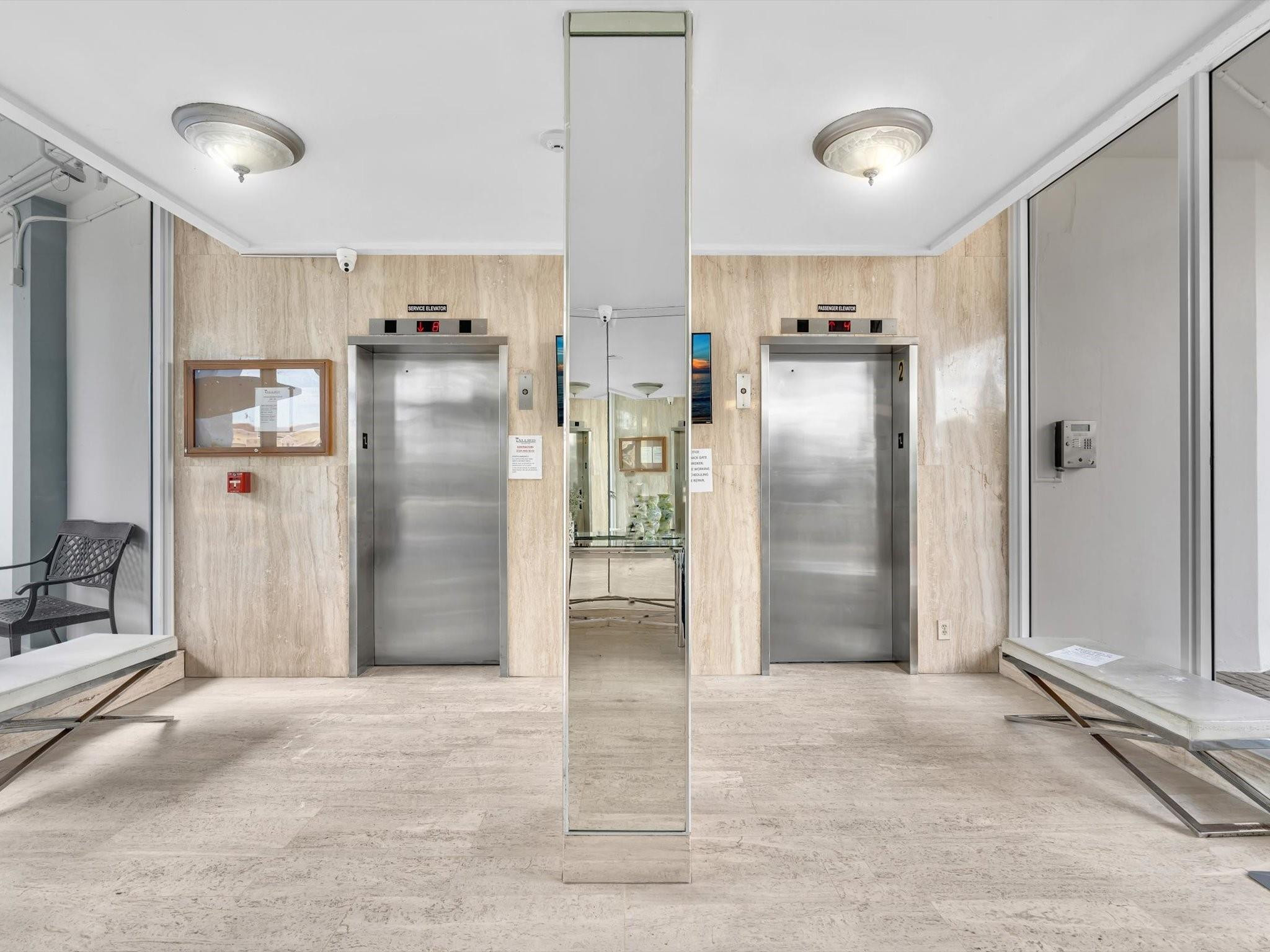 Condominium elevator lobby with two stainless-steel elevators and a mirrored central column.