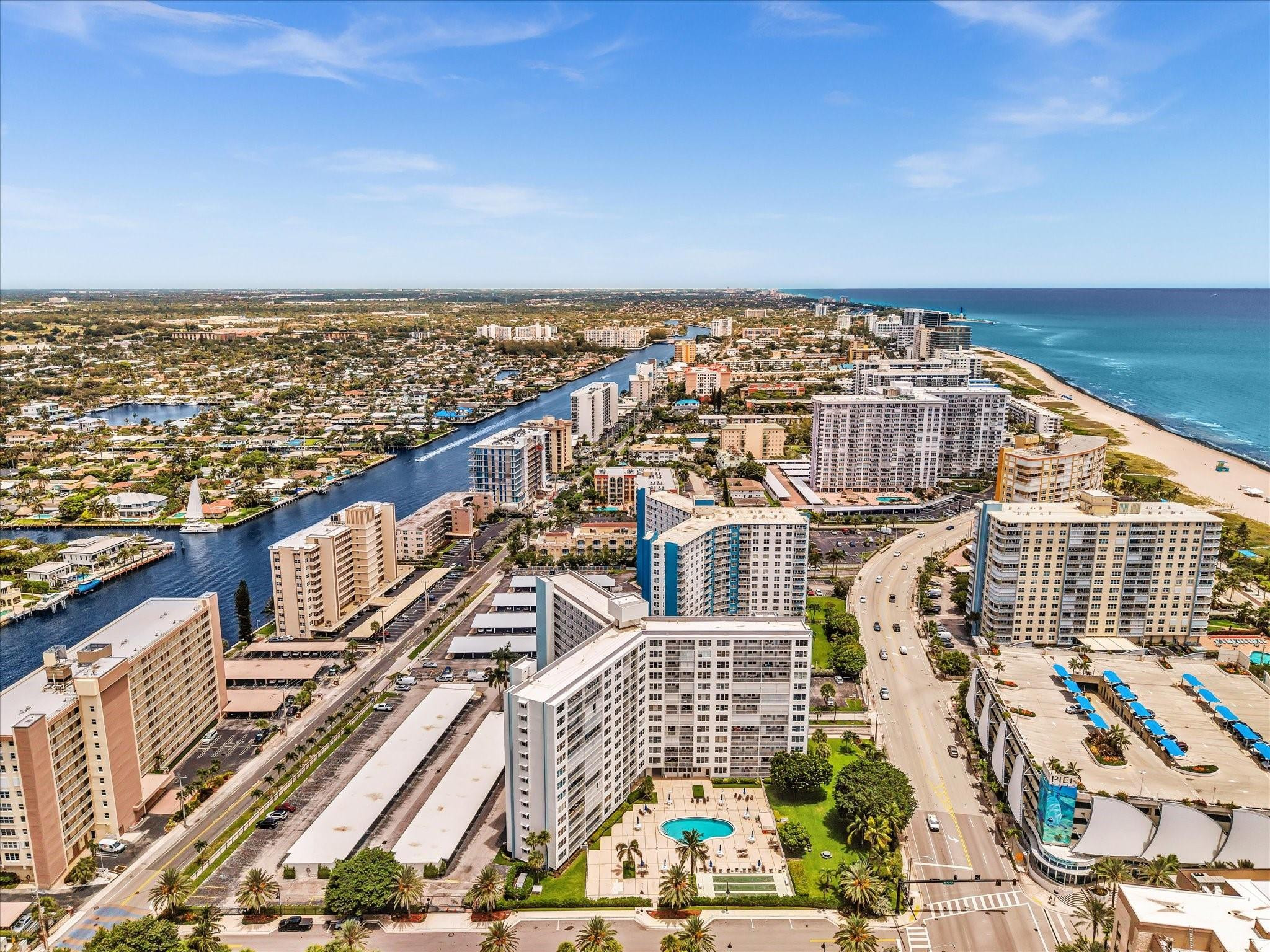 Aerial view of Pompano Beach condos, Atlantic shoreline, sandy beach, and winding canal.