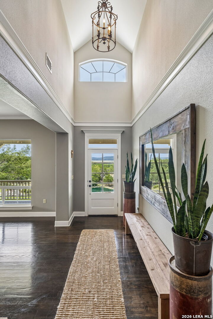 Entry foyer with vaulted ceiling, arched clerestory window, and glass-paneled front door.