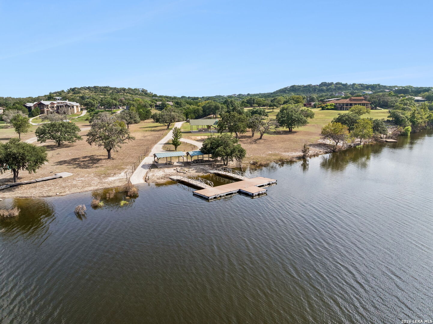 Aerial view of a lakefront property with several docks and homes along the wooded shoreline.
