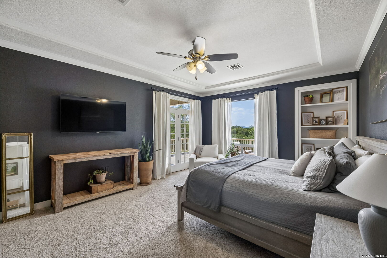 Bedroom with a gray bed, dark walls, and French doors opening to a balcony.