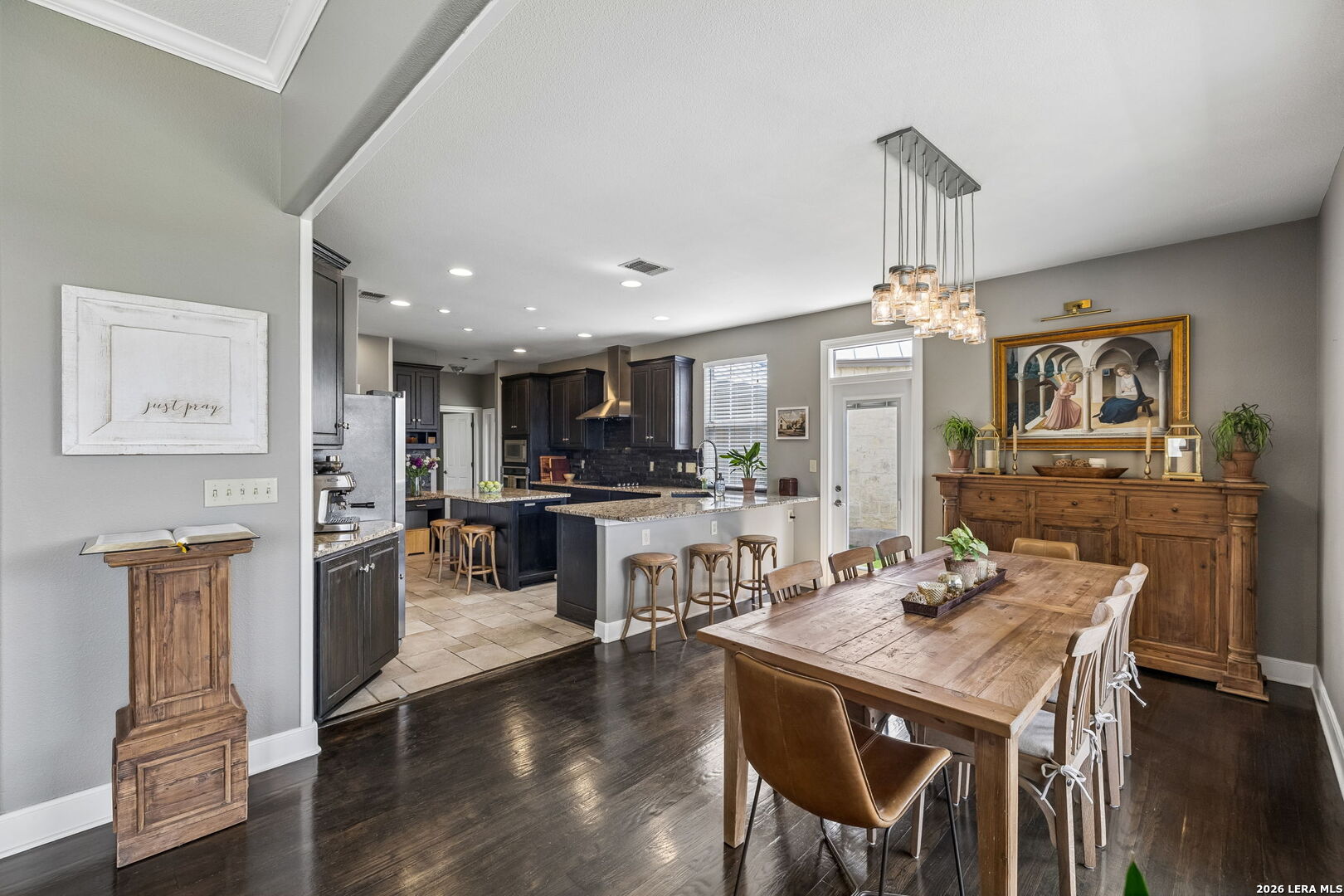 Open kitchen and dining room with a stone island and long wooden table.