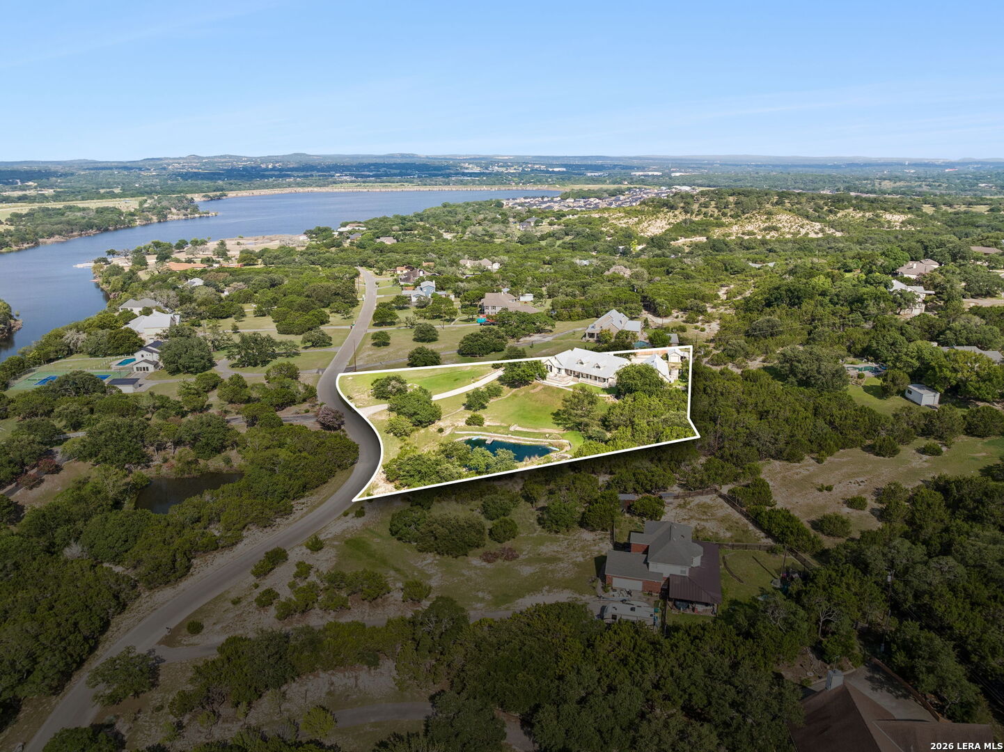 Aerial view of the outlined property, showing a large house, swimming pool, and lake in the distance.