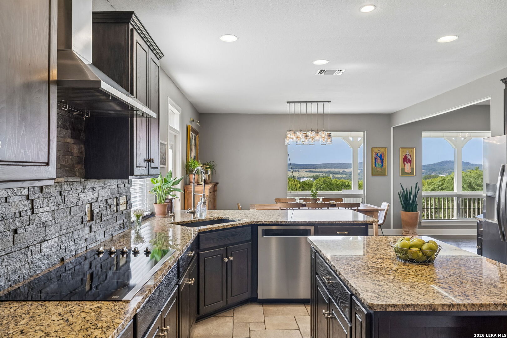 Kitchen with dark wood cabinetry, stone counters, and windows overlooking trees and rolling hills.