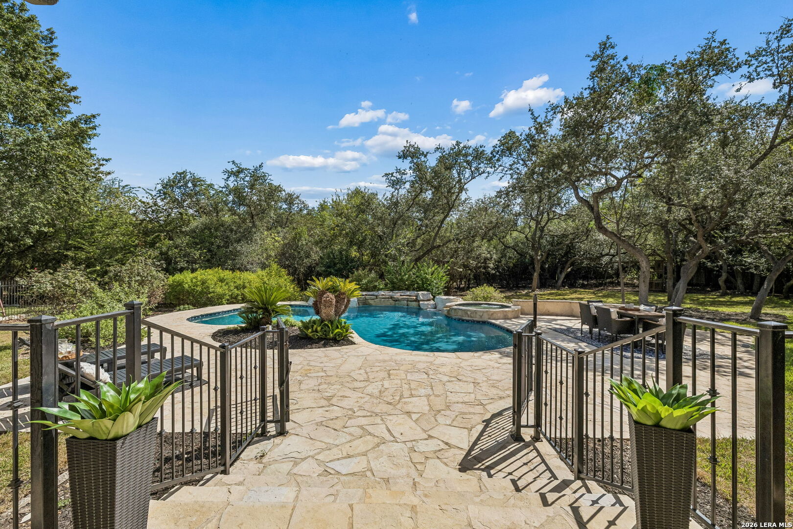 Backyard swimming pool with a raised spa, flagstone patio, and mature trees.