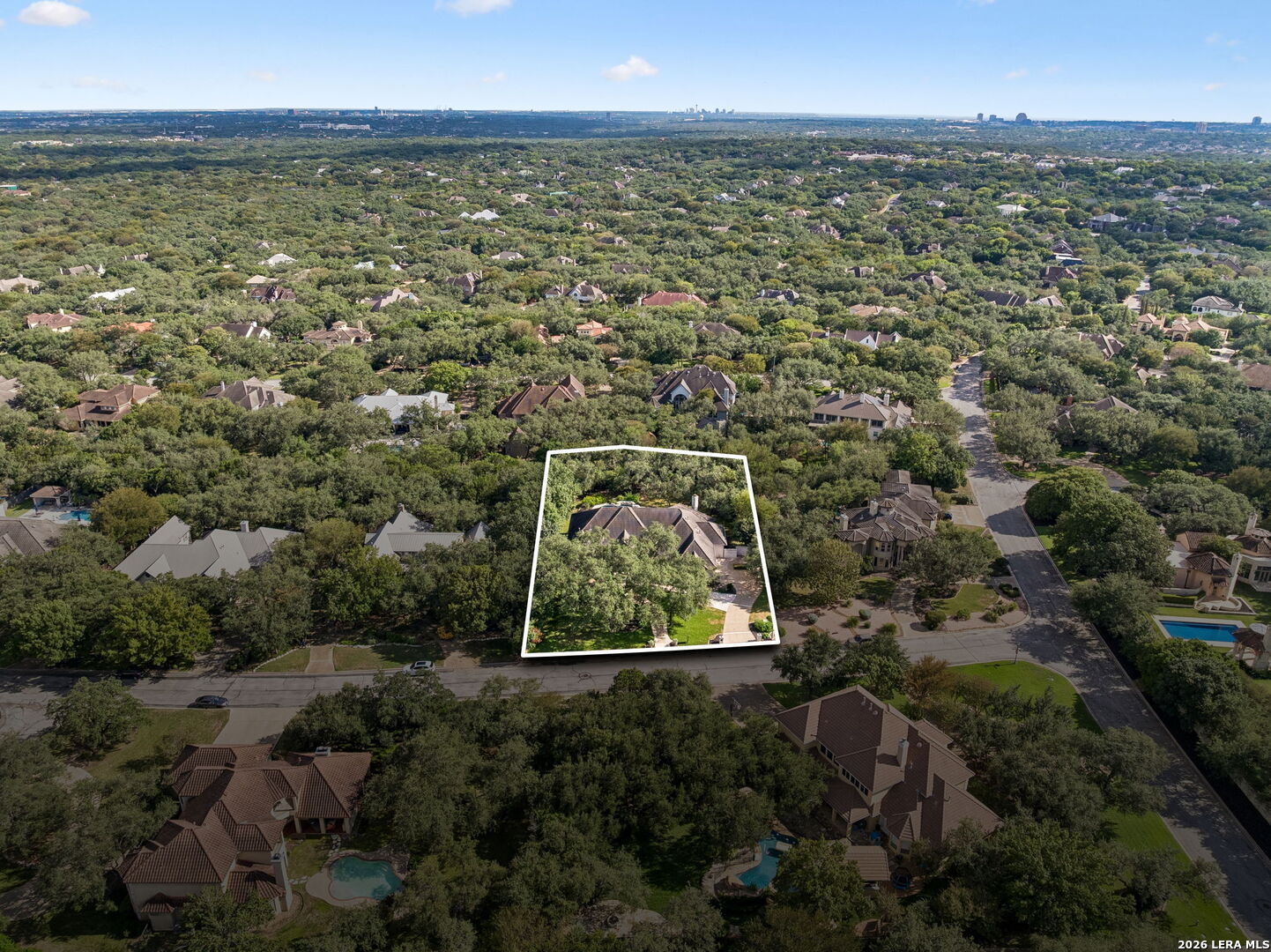 Aerial view of the outlined Pagoda Oak property amid a tree-filled neighborhood, with the distant skyline visible.