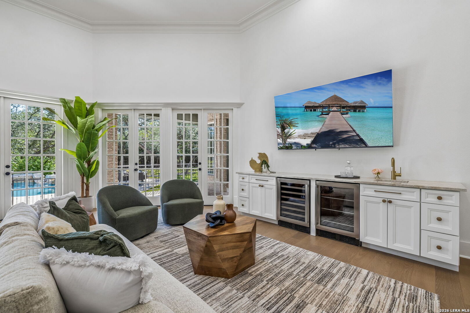 Living room with a built-in wet bar and French doors overlooking the pool.