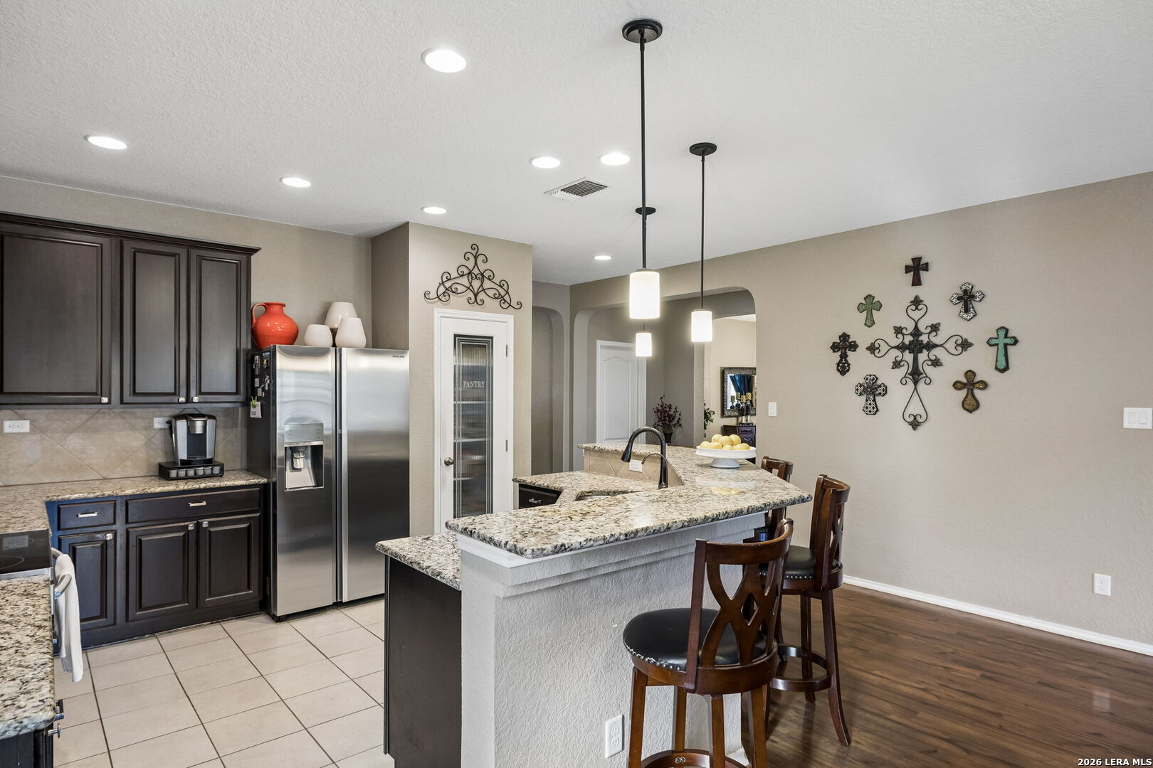 Kitchen with dark cabinets, stainless steel appliances, granite counters, and a breakfast bar with wooden stools.