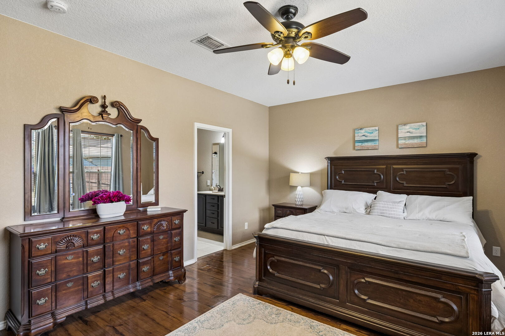 Furnished bedroom with a dark wood bed and matching dresser, hardwood floors, and a ceiling fan.