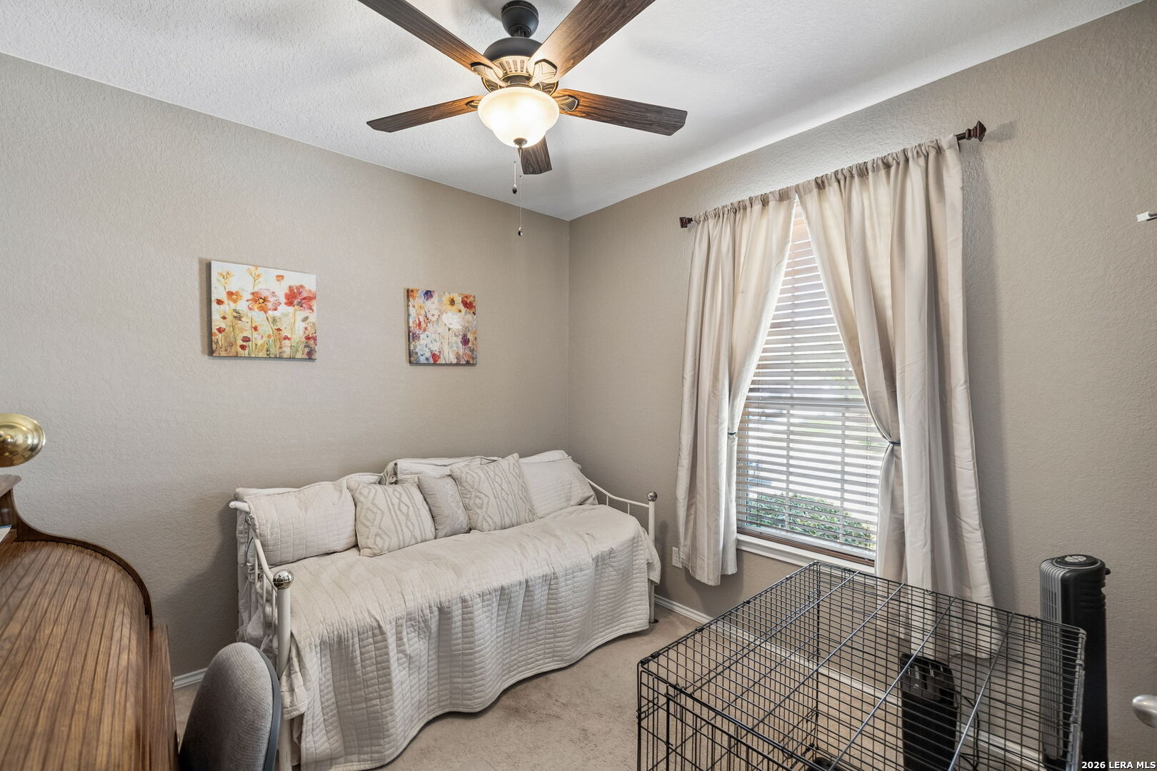 Bedroom with a white daybed, floral wall art, and a curtained window with blinds.